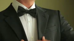 Wedding concept. Close up of groom in tux adjusting his bowtie