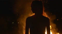 Silhouette of a young woman on in front of fire