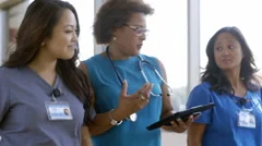 Medical team walking in hospital corridor using digital tablet