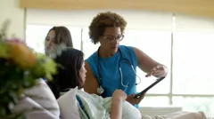 Doctor with digital tablet talking with expectant mother in hospital room