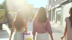 Beautiful woman goes after shopping with full bags. One turns around and smile