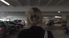 young blonde business woman walking dark lonely car park parking garage