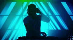 Backlit DJ Playing Music in Nightclub. Silhouette of a DJ