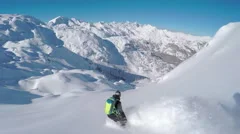 FOLLOW: Extreme freeride snowboarder doing powder turns off-piste in mountains