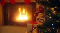 Background with colorful baubles on Christmas tree next to burning fireplace 