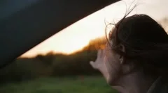 Sunset in the nature. Woman in a car, hand playing in the air. Sunset rays