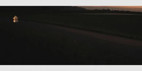 068 Ariel shot starting on the road &amp; panning right to reveal a car travelling Stockbeeldmateriaal 321770853