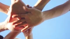 Successful team: many hands holding together on sky background in slowmotion