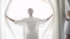 SLOW MOTION: Attractive woman waking up in the morning and opening the curtains
