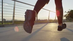 SLOW MOTION: Female runner running across city bridge into magical rising sun