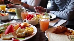 Table with food and glasses of juice, hands of eating people