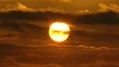The floating sun in dense rain clouds. Evening, sunset. Time-lapse.