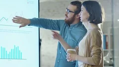 Young Man and Woman Discuss Charts Drawn on Their Electronic Whiteboard.