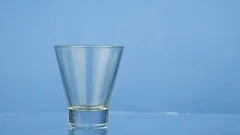 Empty glass being filled with milck on blue background