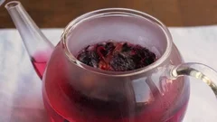 Boiling water being poured into a teapot with hibiscus tea