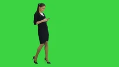 Young businesswoman checking her mobile phone while walking on a Green Screen