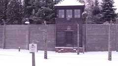 Steadicam shot of barbed wire fence and guard tower of a concentration camp in