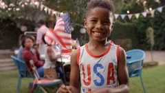 Young black boy waving US flag at 4th July family barbecue
