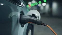 Senior is plugging in power cord to an electric car. Close up. 4K