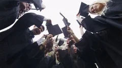 4K Happy students on graduation day throwing caps into the air
