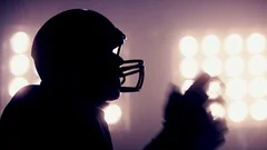 American football player putting on helmet against stadium illumination lights