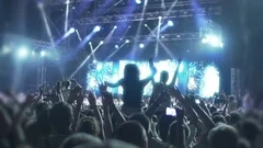 Crowd of music fans dancing under luminous rays of LED illumination, concert