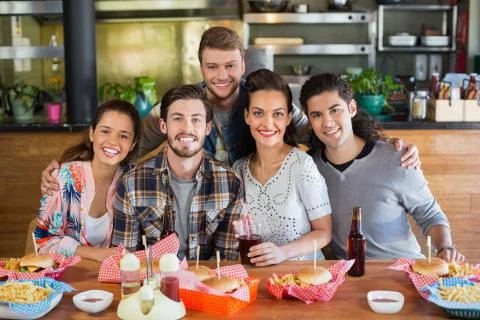 Portrait of smiling friends enjoying in restaurant xkwx 20s, Young Adult, Man, Male, Caucasian, Mixed-race, Woman, Female, Cheerful, Friend, Beer, Pub, Restaurant, Party, Celebration, Fun, Leisure, Excitement, Laughing, Cheering, Clubbing, Event, Amusement, Enjoyment, Joy, Pleasure, Enjoying, Amusing, Entertaining, Holding, Alcohol, Attractive, Beautiful, Casual, Clothes, Fashion, Lifestyle, Style, Trendy, Drink, Sitting, Togetherness, Smile, Happiness, Hipster, Friendship, Together, Table, Food, Burger, Fast Food, French Fries, Indoors, Looking At Camera, REUNITEDP5BRIEF