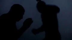 Silhouettes kick boxers fight in dark. Closeup of mma fighter silhouettes