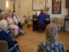 Old people listen to the piano in retirement home dolly shot