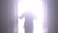 Man silhouette back going to the light at night. Man open door light in dark