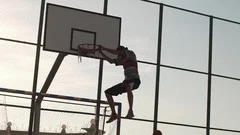 Caucasian male player in streetball doing two-handed slam dunk on outdoor sports