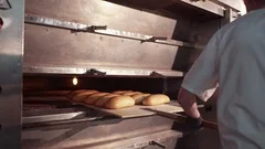 A male baker in a white uniform takes out of the oven just baked bread, places