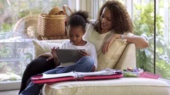 Mother watching daughter using digital tablet
