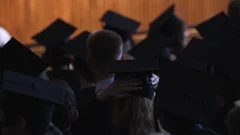 Students in black gowns and caps sitting at graduation ceremony, future