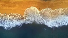 AERIAL TOP DOWN: Two guys walking along the ocean leaving footprints in the sand