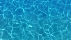 Pure blue water in the pool with light reflections. Slow motion.