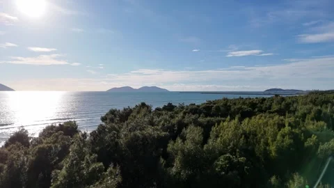 08 Drone shot over forest and coastline with sea and mountains horizon Stock Footage 332560492