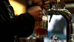 Male hands pouring beer in glass mug from tap. Fresh draft beer in pub
