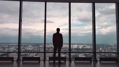The businessman stand near the panoramic window on the morning city background