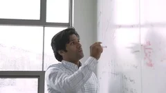 Indian businessman talking and writing on whiteboard in meeting