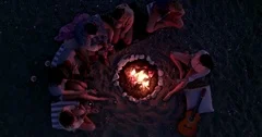 Birds eye view of friends roasting marshmallows sitting around campfire