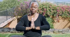 Lively retired African American woman puts her hands together in a namaste