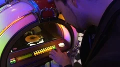 Man trying to choose good song on old jukebox dropping coin and pushing keys