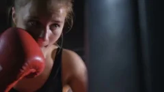 A girl is a boxer. The girl is training in the boxing hall.