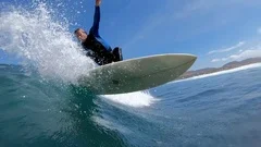 SLOW MOTION: Surfer dude making a sharp turn on surfboard and splashes camera.