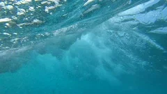 SLOW MOTION, UNDERWATER: Large deep blue ocean waves breaking and splashing.