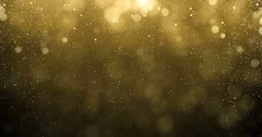 Gold particles of glitter fallling down with bright bokeh shine effect. Looped
