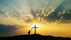 Silhouette of woman praying at Cross over beautiful sky