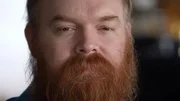 Close up to man with thick red beard with sad face