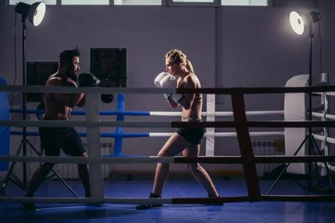 Young woman exercising with trainer at boxing and self defense lesson ...